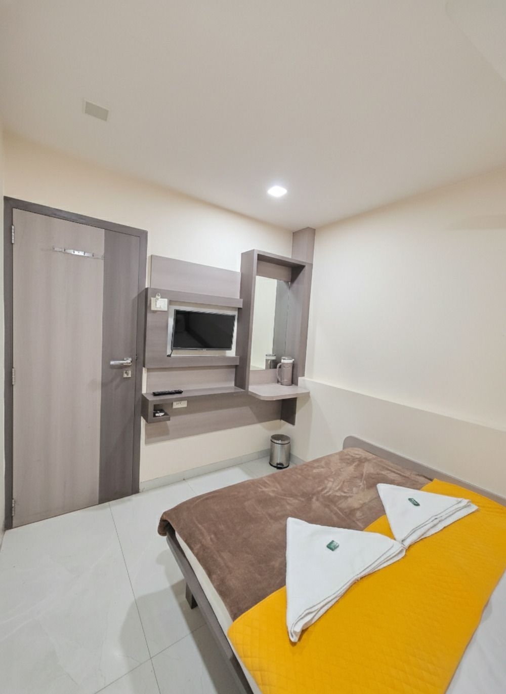 A bedroom with a bed, a wardrobe, a mirror, and a small shelf with a kettle.