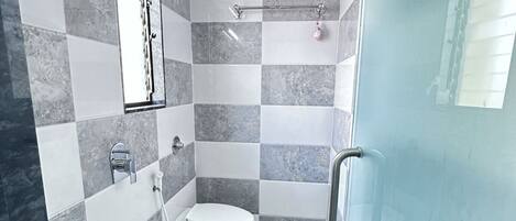 A modern bathroom with a glass shower enclosure, a white toilet, and a sink with a black countertop.