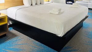Ein Hotelzimmer mit einem großen Bett, zwei Nachttischlampen, einem Holz-Kopfteil und einem Fenster mit Vorhängen.