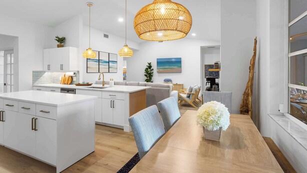 Una cocina moderna con armarios blancos, una isla central e iluminación colgante.