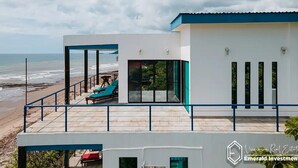Una moderna proprietà sul lungomare con un balcone vista oceano, completa di piscina e lettini.