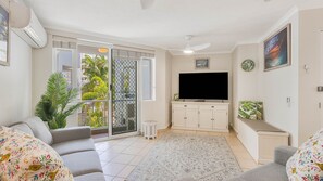 Ein Wohnzimmer mit Fernseher, Sofa und Blick ins Freie.