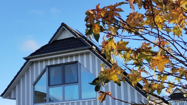 Ein modernes, zweistöckiges Haus mit großen Fenstern, einer Garage und einem gepflegten Rasen.