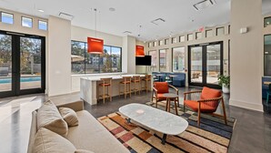 A modern interior with a sofa, coffee table, and bar area with stools. - Stylish BeltLine 1BR with Pool-View Balcony, EV Charging & Gym Next Door (Atlanta)