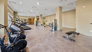 A spacious gym with cardio machines, weight stations, and a bench. - Stylish BeltLine 1BR with Pool-View Balcony, EV Charging & Gym Next Door (Atlanta)