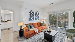 A modern living room with a sofa, coffee table, and a view of a balcony. - Stylish BeltLine 1BR with Pool-View Balcony, EV Charging & Gym Next Door (Atlanta)