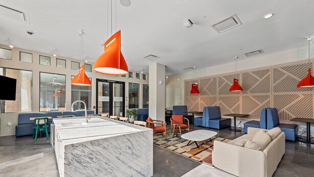 A modern lobby with a marble reception desk, blue seating, red pendant lighting, and a geometric patterned wall. - Stylish BeltLine 1BR with Pool-View Balcony, EV Charging & Gym Next Door (Atlanta)