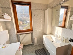 A bathroom with a window, a bathtub, a toilet, and a sink. - Apartment Hamburg Balcony Lake View (Tignale)
