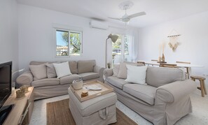 Ein modernes Wohnzimmer mit zwei Sofas, einem Couchtisch, einem Fernseher und einem Essbereich mit Tisch und Stühlen.