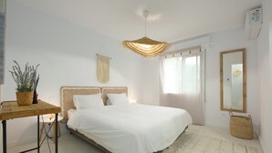 Un dormitorio con cama, mesita de noche, lámpara y un aplique.