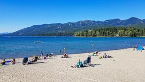 Une plage où des gens se détendent, un ciel bleu clair et des montagnes en arrière-plan.