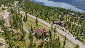 Ein abgelegenes Ferienhausgebiet mit mehreren Häusern, umgeben von dichtem Wald, einer kurvenreichen Straße und einem See im Hintergrund.