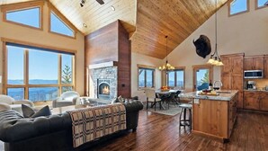 Ein geräumiges Wohnzimmer mit Kamin, Essbereich und Küche mit Holzausstattung sowie einem Steinkamin.