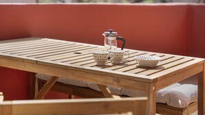 A wooden table with a coffee pot, two cups, and a bowl.