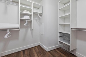 A walk-in closet with open shelves, hanging space, and wire baskets. - Stylish Seaport Apt Near Waterfront (Boston, MA)