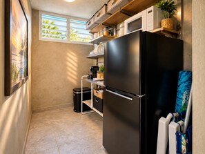 A compact kitchen with a black refrigerator, a microwave, and a small window with blinds. - Serene Coastal Studio with King Bed & Balcony (Luquillo)