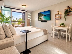 A modern hotel room with a bed, a desk, and a view of a tropical beach. - Serene Coastal Studio with King Bed & Balcony (Luquillo)