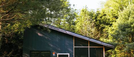 Een modern huis met een grote glazen deur, een klein portaal en een stenen pad dat naar de ingang leidt.
