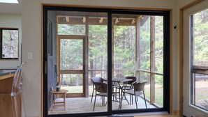 A room with a large sliding glass door leading to an outdoor deck with a table and chairs.