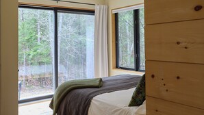 A bedroom with a bed, a window, and a wooden wall.