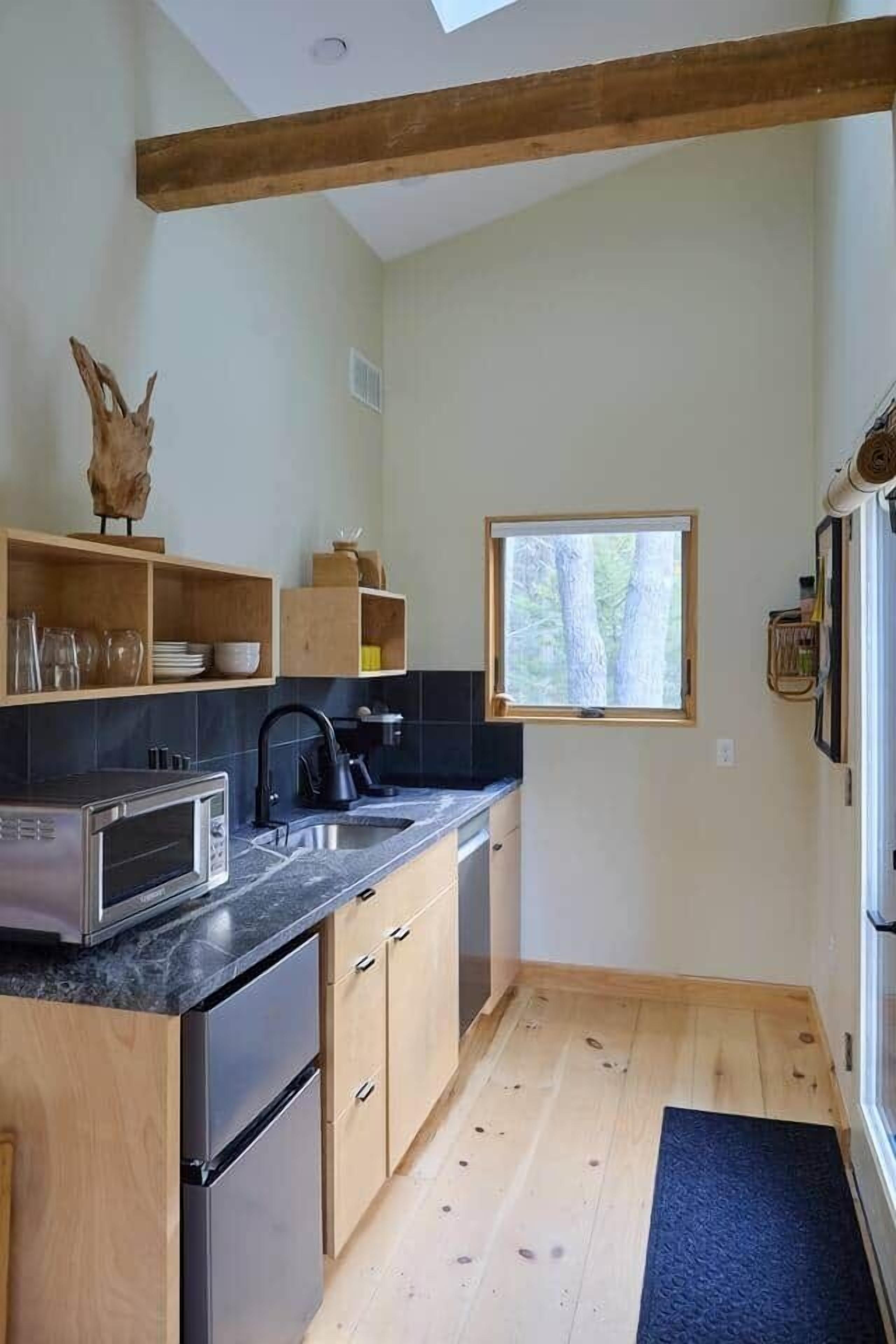 A modern kitchen with wooden cabinets, a black countertop, and a window providing natural light.