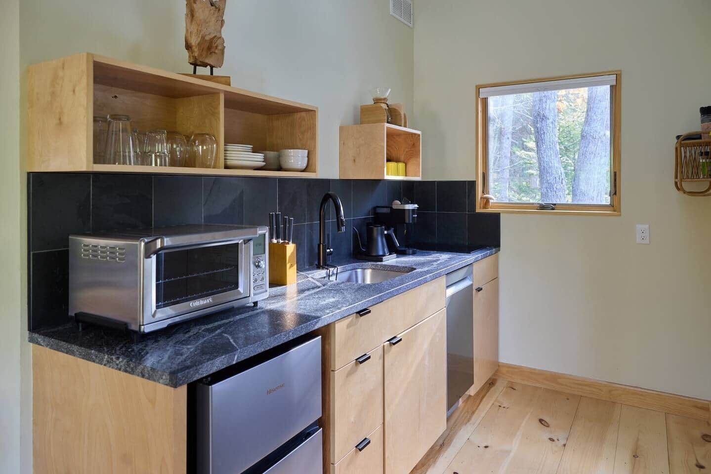A modern kitchen with a built-in microwave, a sink, and wooden cabinets.
