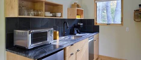 A modern kitchen with a built-in microwave, a sink, and wooden cabinets.