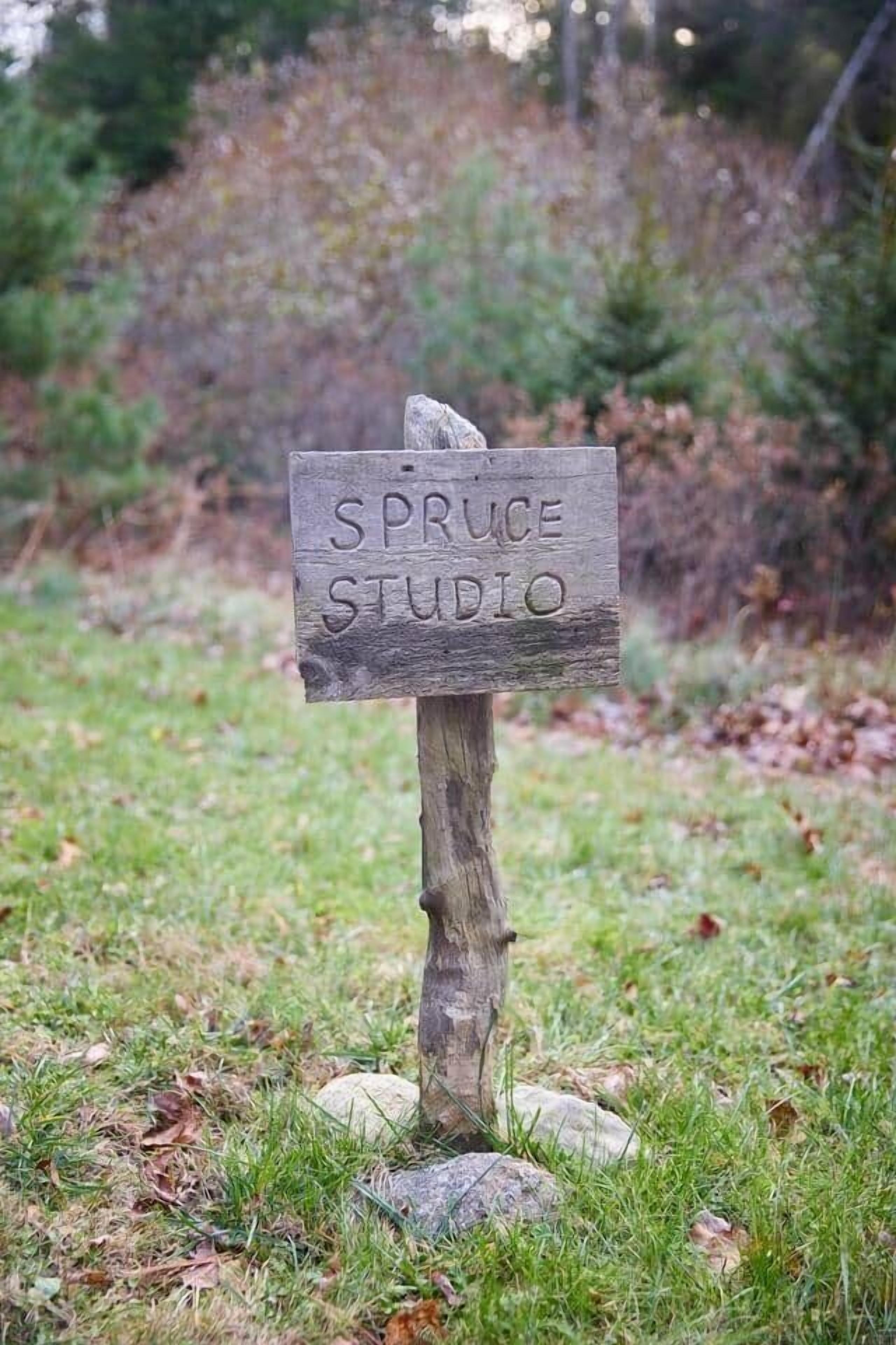A wooden sign with the text "SPRUCE STUDIO" mounted on a post.