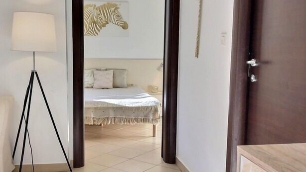 Une pièce avec un lit, une lampe et une porte donnant sur une autre pièce.