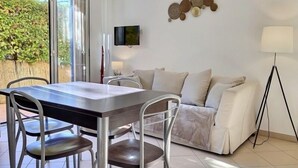 Un salon moderne comprenant un coin repas, un canapé, un téléviseur et un lampadaire.