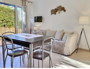 A modern living room with a dining area, a sofa, a TV, and a floor lamp.