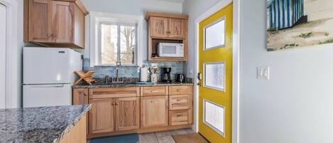 A kitchen with wooden cabinets, a white refrigerator, a microwave, and a coffee maker.