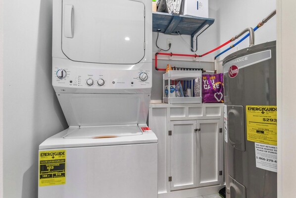 Una cocina compacta con lavadora blanca, microondas y refrigerador.