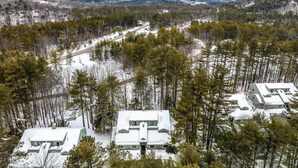 A snow-covered cabin complex surrounded by dense forest and mountains. - 3 Mi to Story Land: All-Season Family Condo (Bartlett)