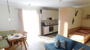 A compact living space with a dining area, kitchenette, and a sofa with a patterned cushion. - Apartment 'Am Rosengarten' with Wi-Fi and Air Conditioning (Füssen)