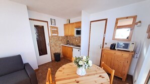 A compact living space with a dining area, kitchenette, and a sofa. - Stay at the slopes, stunning mountain views! (Le Grand-Bornand)