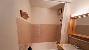 A bathroom with a bathtub, a sink, and a mirror. - Stay at the slopes, stunning mountain views! (Le Grand-Bornand)
