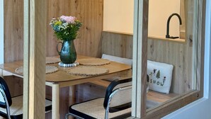 Un coin repas avec une table en bois, des chaises, un vase de fleurs et un miroir.