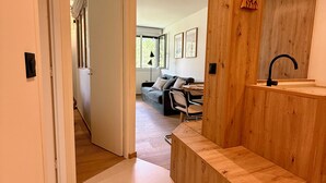 Un intérieur moderne avec un banc en bois, un évier et une vue sur un espace de vie comprenant un canapé et des fauteuils.