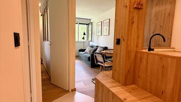 Un interior moderno con un banco de madera, un lavabo y vistas a una sala de estar con sofá y sillones.