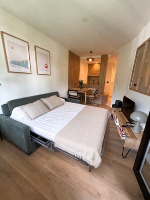 Une chambre à coucher de taille réduite, comprenant un lit, une table de chevet et un petit bureau avec une lampe.