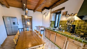 A kitchen with a wooden table, chairs, a tiled floor, and a green-tiled backsplash. - Large family home near lake and resorts (Saint-André-d'Embrun)