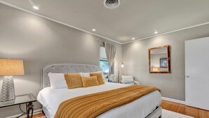 Una camera da letto moderna con un letto grande, un comodino, una lampada e uno specchio appeso al muro.