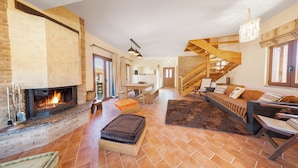 A spacious living room with a fireplace, a wooden staircase, and a cozy seating area. - Anemos Mountain Villa - Your Perfect Mountain Retreat (Arachova)