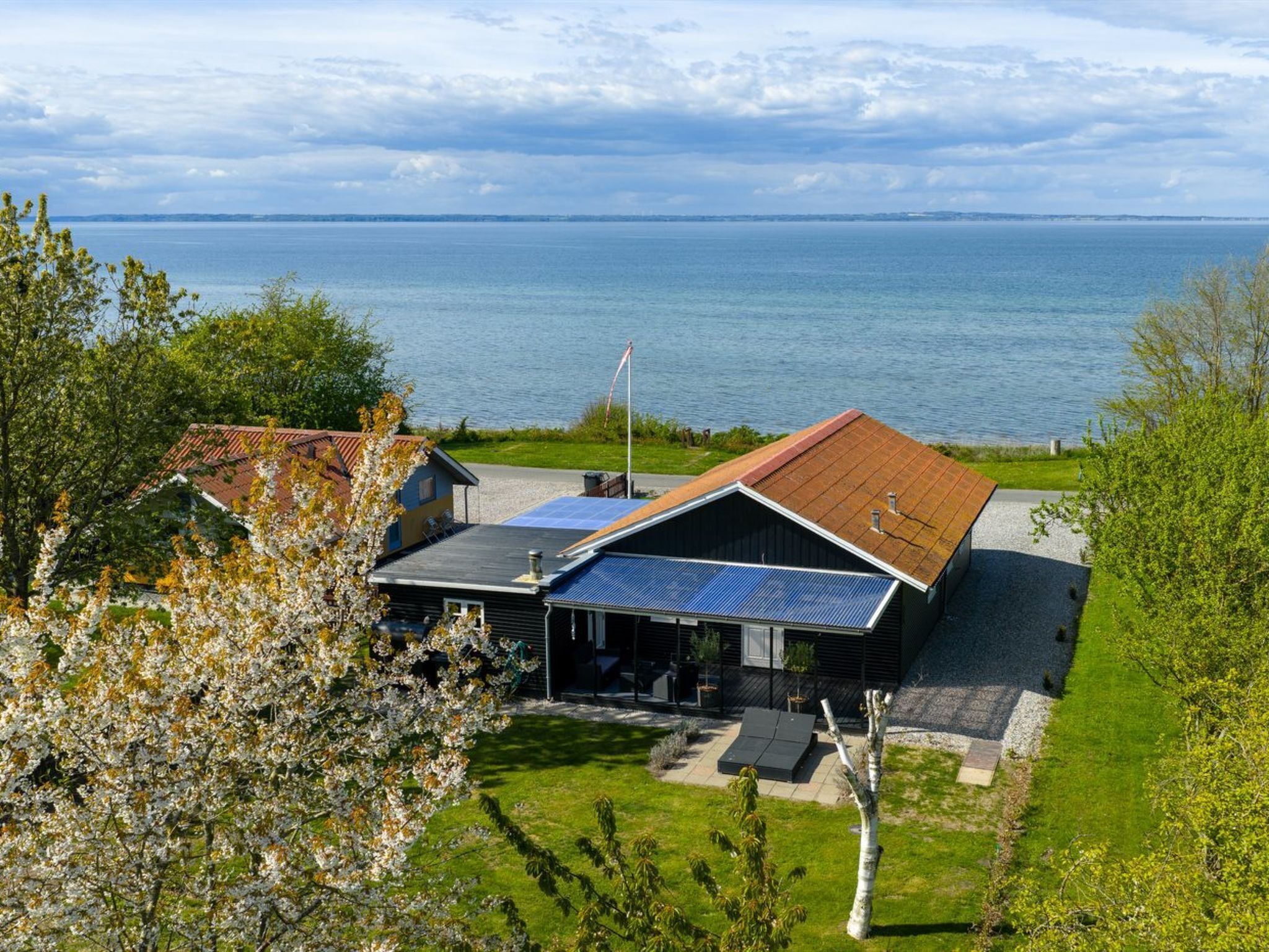 Et hus med solpaneler på taget, en swimmingpool og havudsigt.