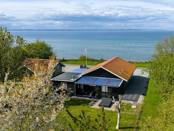 A house with a solar panel roof, a swimming pool, and a view of the sea.