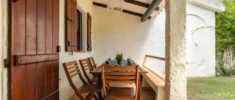 A wooden table with chairs, a hanging light fixture, and a view of a garden.