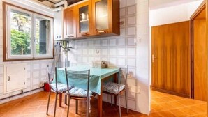 A dining area with a table and chairs, wooden cabinets, and a window with a view of greenery. - Cà San Cosmo (Venezia)
