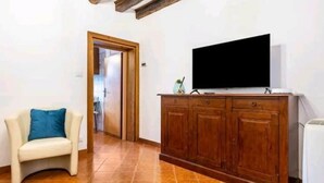 A room with a wooden cabinet, a television, and a chair. - Cà San Cosmo (Venezia)