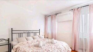 A neatly made bed with a floral bedspread, a black metal headboard, and white pillows. - Cà San Cosmo (Venezia)
